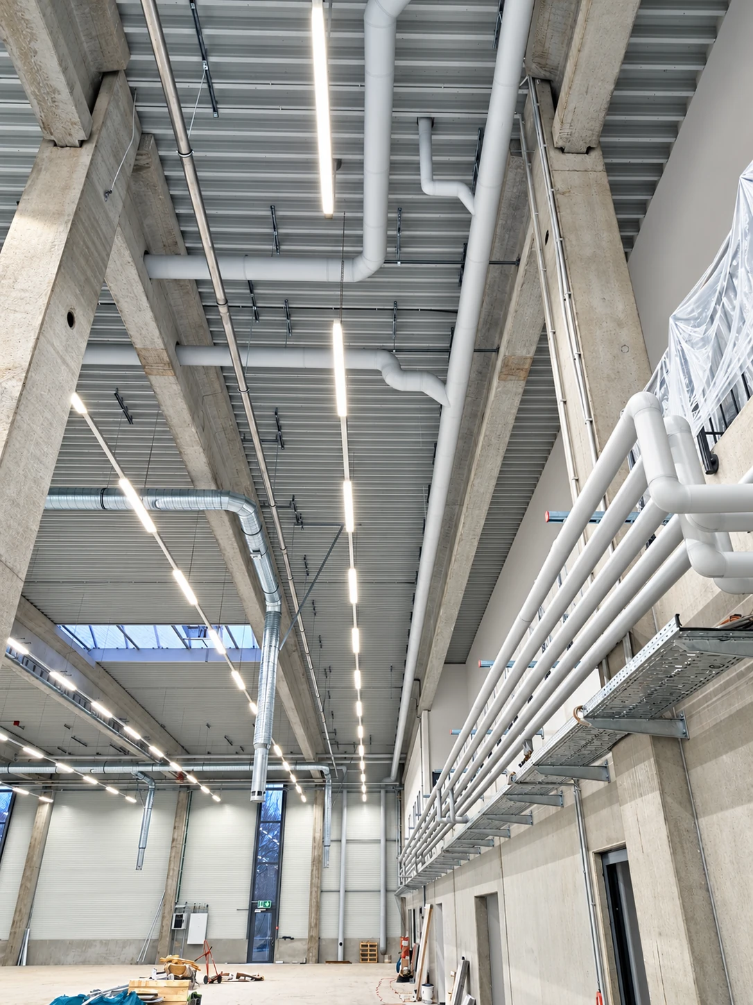 Halleninnenraum mit weißen Rohrleitungen und sichtbarer Gebäudetechnik